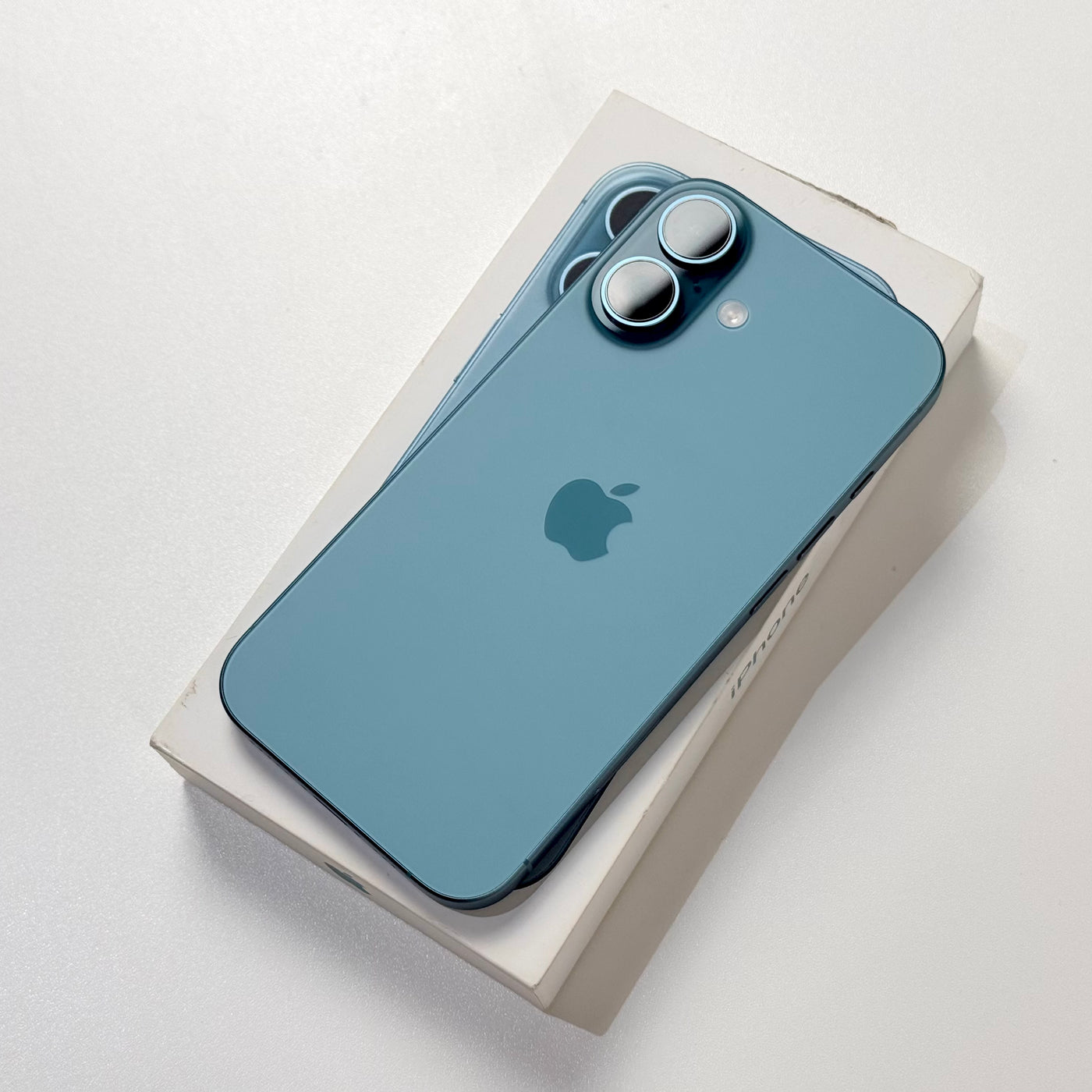 Pre-owned iPhone 16 Teal back view with dual camera, on original box - MacShack