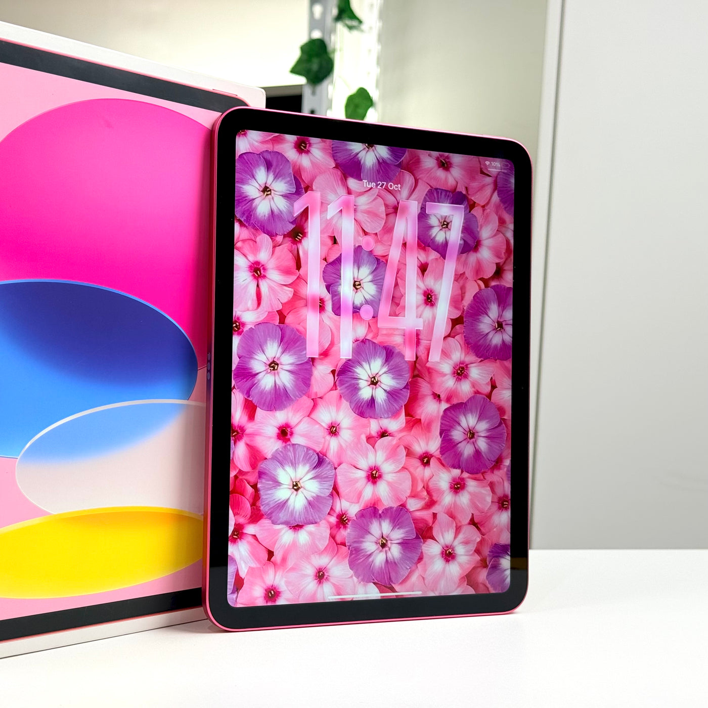Pre-owned iPad 11-inch A16 Pink standing upright, screen on, beside original box - MacShack