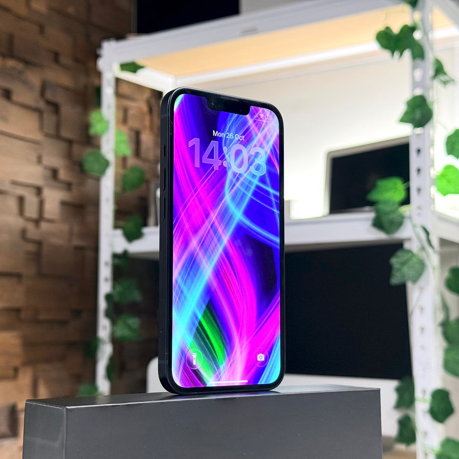 Pre-owned iPhone 13 Midnight standing upright on shelf, front screen view - Mac Shack