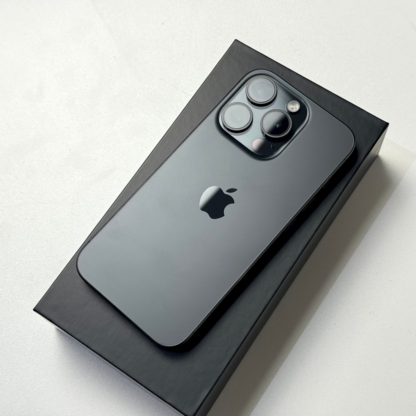 Pre-owned iPhone 15 Pro Black Titanium, back view showing the titanium finish and triple camera