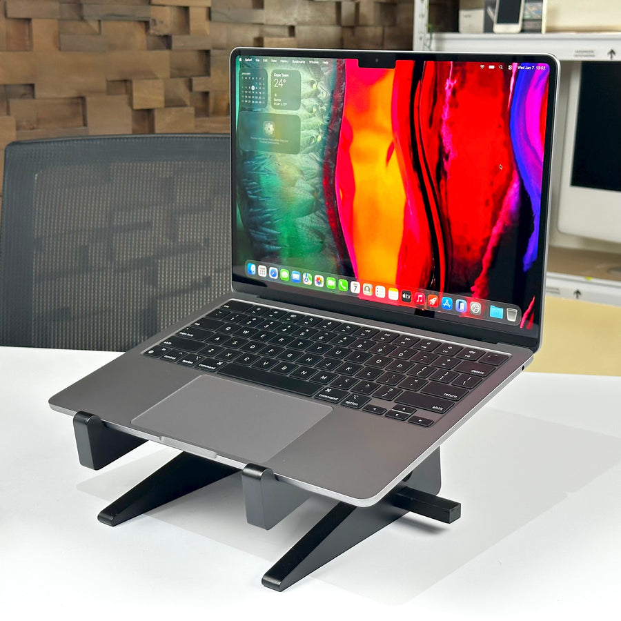 Angled view of the pre-owned MacBook Air M2 in Space Gray, open on a laptop stand - Mac Shack