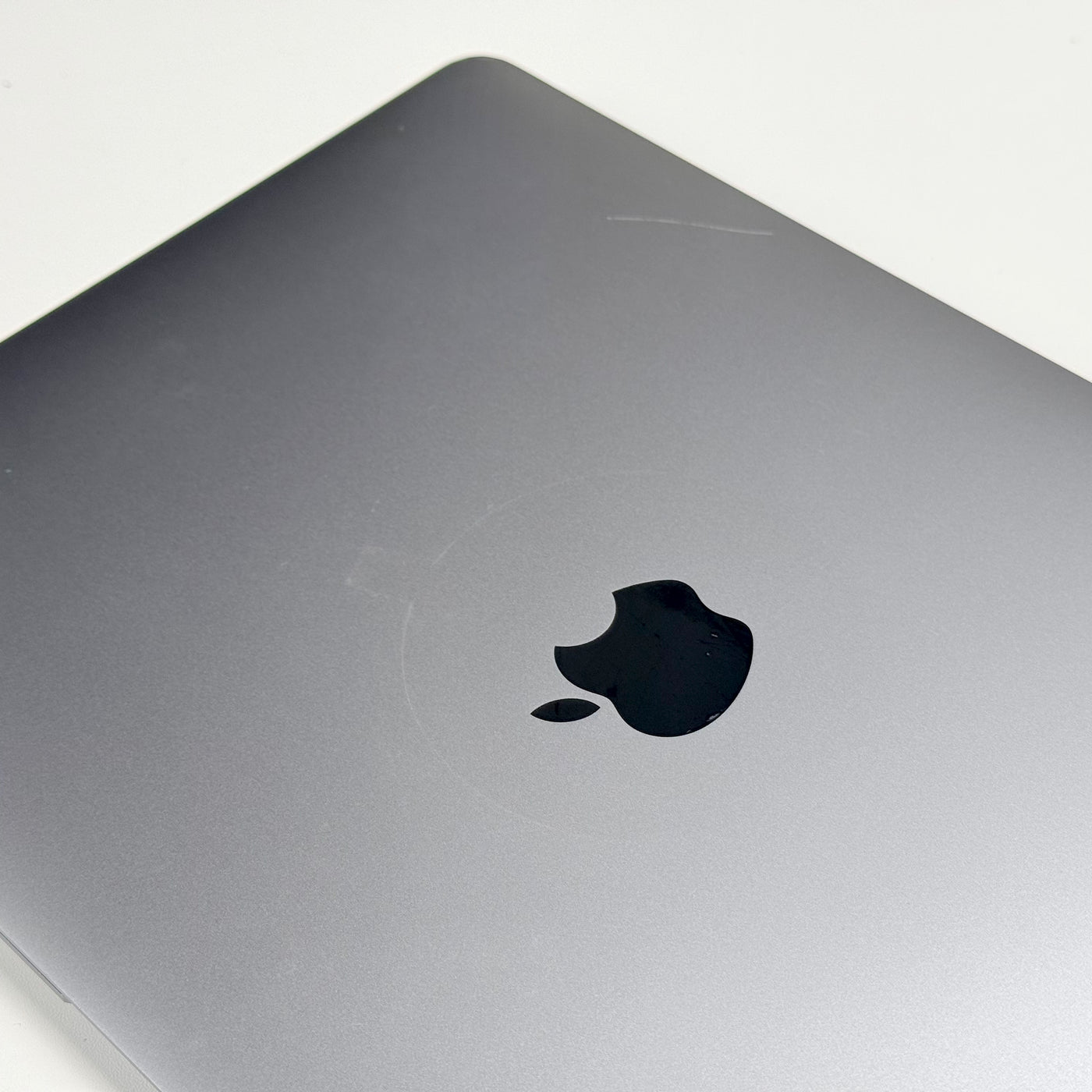 Close-up of the lid on the pre-owned MacBook Air M1, showing surface scratches and the Apple logo - Mac Shack